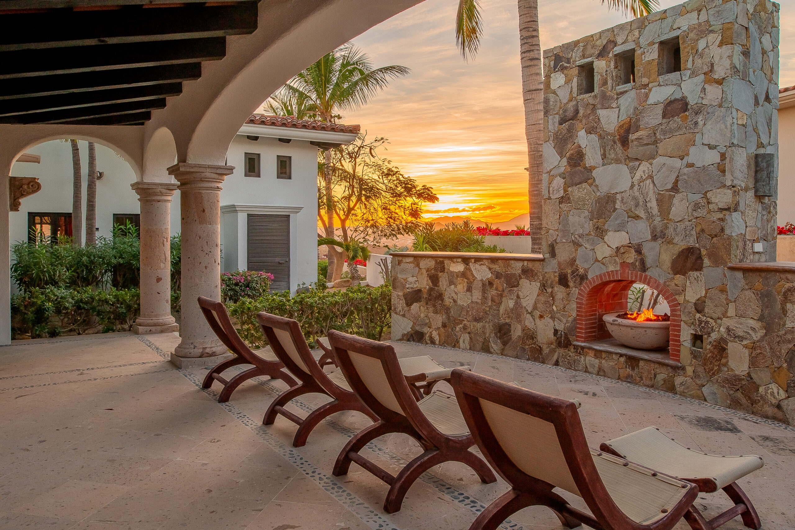 Luxury Los Cabos villa terrace with stone fireplace at sunset, managed by AMG Property Services